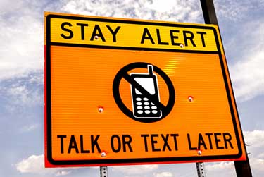 Stay alert sign saying text or talk on phone later