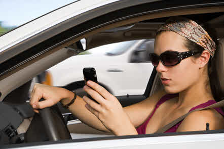 woman driving while looking at her phone