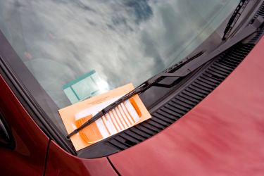 red car with parking ticket on dashboard
