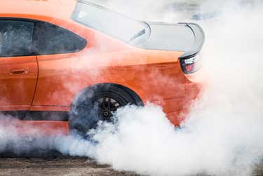 An orange car doing a burnout 