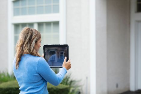 woman in blue shirt photographing a house