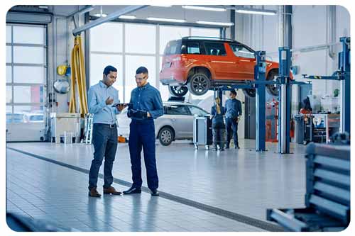 Car service employees talk while standing in a garage.