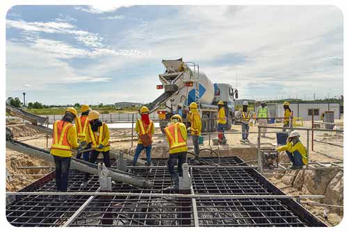 concrete contractors pouring concrete during commercial concreting floors of building in construction site.