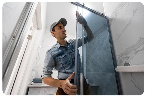 handyman installing glass cabinet in bathroom.