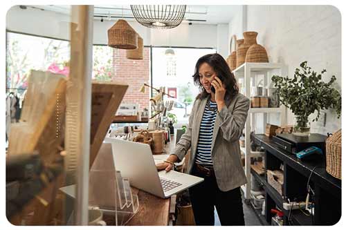 shop owner standing behind a counter working on a laptop