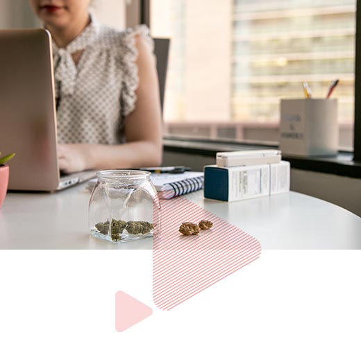 woman typing on a laptop with cannabis in a jar