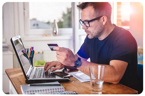 man at her credit card in front of laptop 