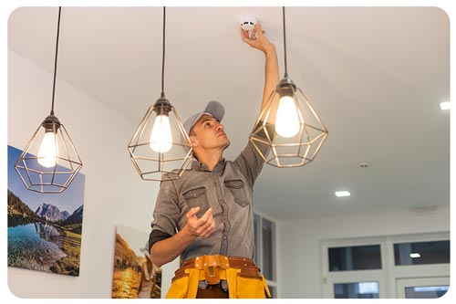 handyman installing a smoke detector on the ceiling