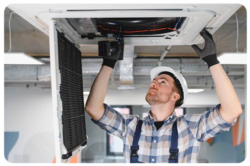 Hvac technician repairing air conditioning unit on ceiling