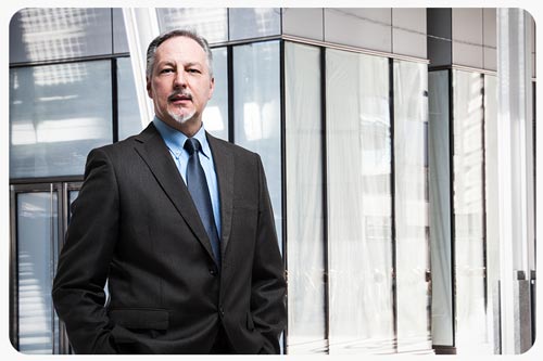 a senior businessman in a suit is standing in front of a conference room.