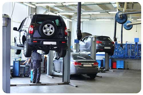 Three cars in auto repair garage with mechanics working
