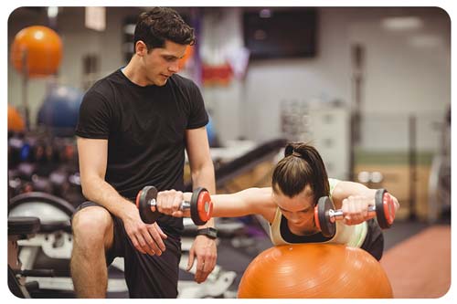 woman working out with trainer at the gym
