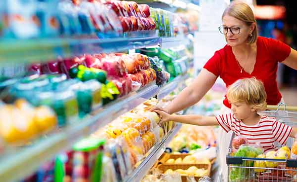 mom and little boy buy fresh mango in grocery store