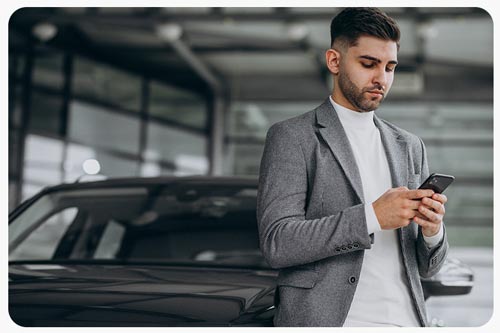Young man using a driving app car leaning on car