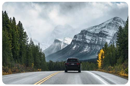 car driving on highway in the forest with mountain in B.C.