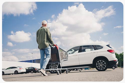 a man shopping cart loading trunk car mall parking outside