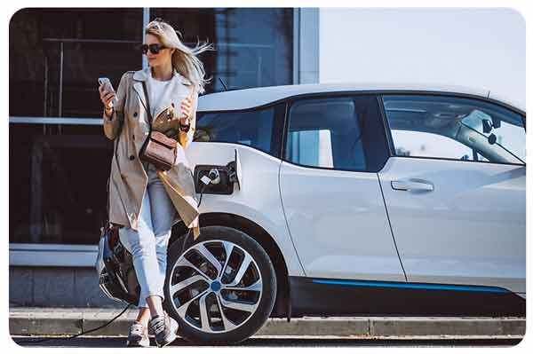 Women standing in front of electric car while it charges