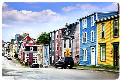 A car parked on  the side of road with colorful houses.