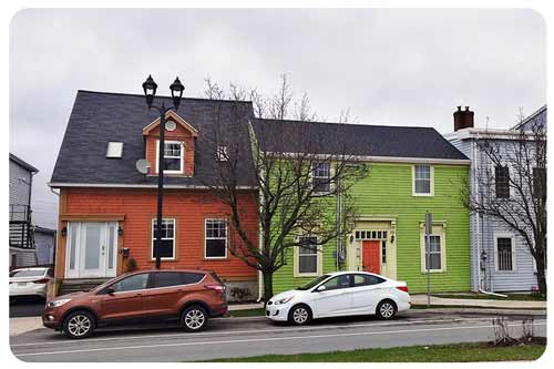 cars are parked in froont of colourful wooden row houses