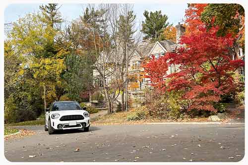 A white compact car drives along the colorful street