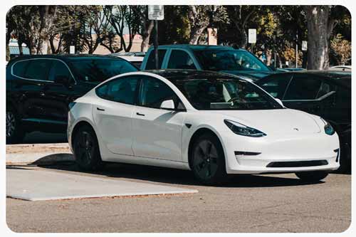 white Tesla at charging station