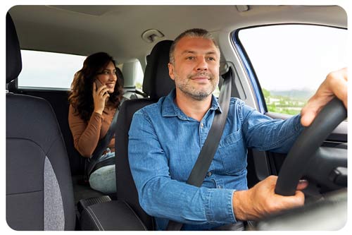 Male Uber driver focused on the road with a female passenger in the back seat