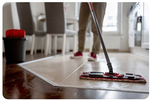 woman mops floor in kitchen at home