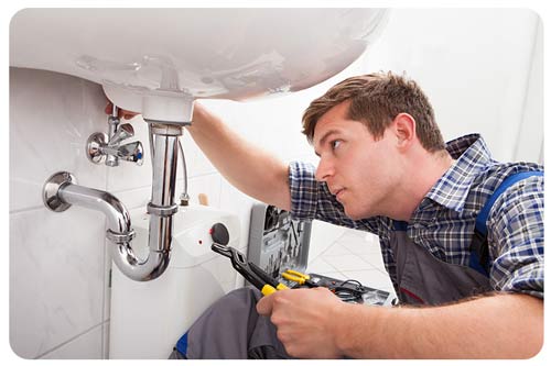 a plumber fixing a sink in bathroom