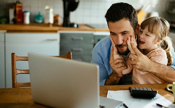 father and daughter smiling looking at a laptop