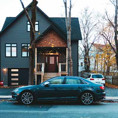 Black car parked on street in front of a house