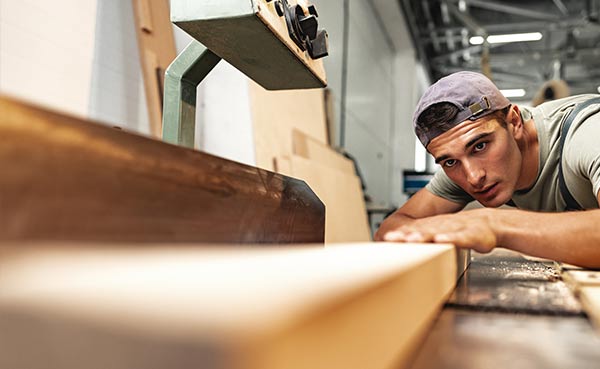 Carpenter measuring wood in workshop, carpenters insurance