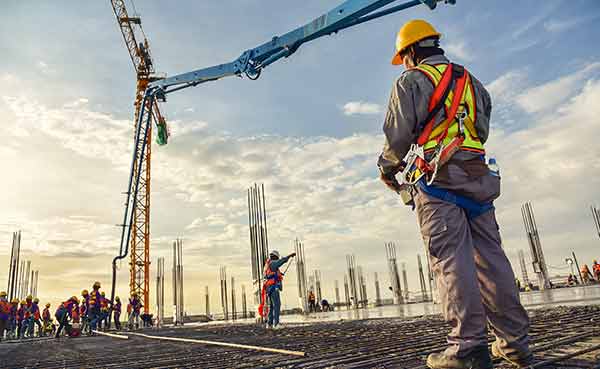concrete contractors control a pouring concrete pump on construction site
