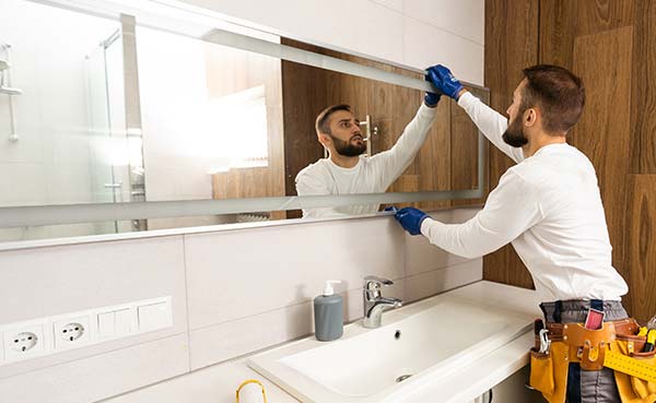 handyman installs the mirror in the bathroom.