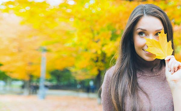 young woman hiding behind a yellow leaf