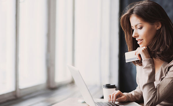 a young woman holding credit card and using laptop computer