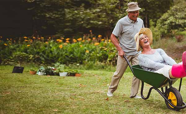 happy senior couple playing with a wheelbarrow in a sunny day