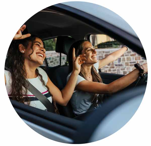 A woman driving is having a good time with her friend.