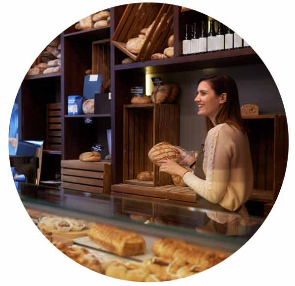 female owner holding bread working at her bakery store.
