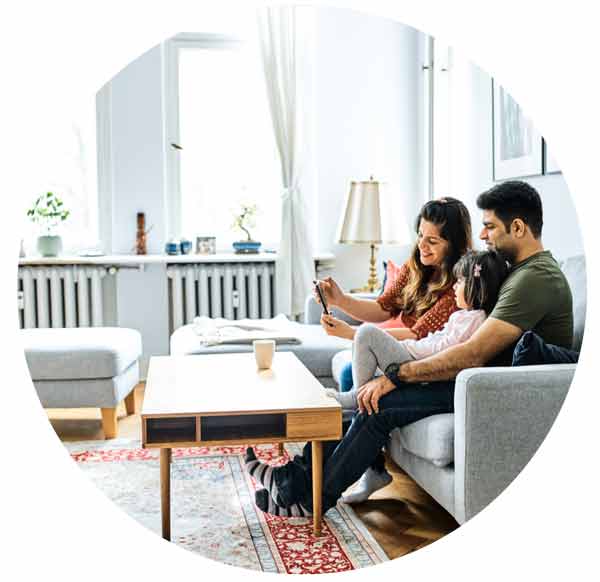family sitting on sofa watching a mobile phone together in their living room