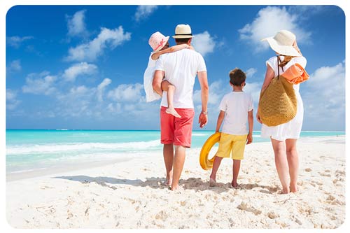 family walking on sandy tropical beach on a sunny day