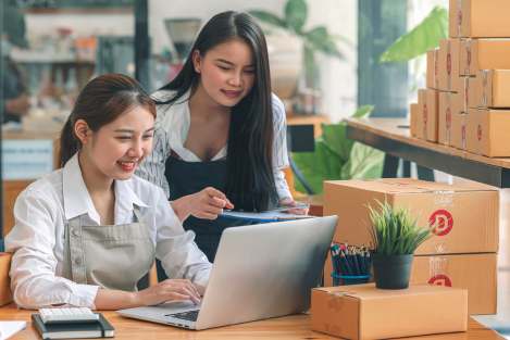 two Asian women reviewing computer documents