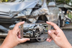 person taking picture of damaged car after an accident