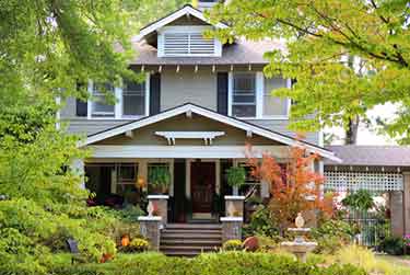 white and grey house with trees and a garden