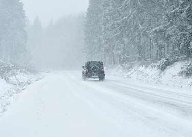 Jeep driving a country road in a snow storm