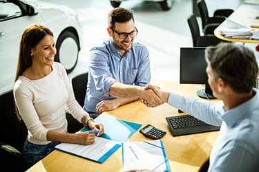 people shaking hands at car dealership