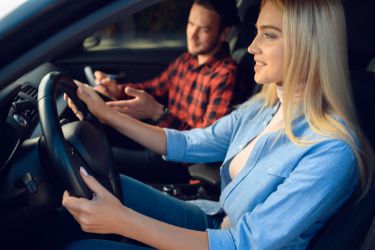 blonde woman with driving teacher inside a car