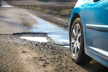 blue car driving over potholes