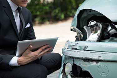 insurance claims adjuster looking at a damaged car