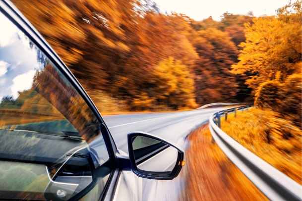 car driving down rural highway in autumn