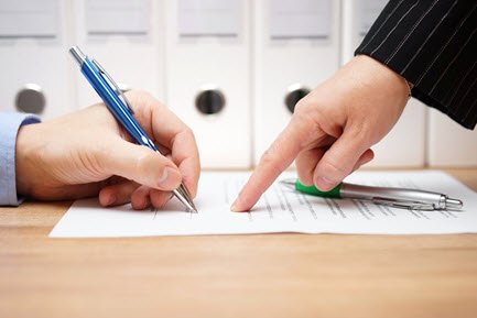 Person signing a paper document with a pen
